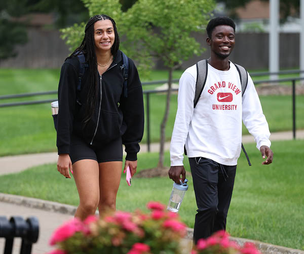 Grand View students studying together in lawn chairs outside near the residence halls on their laptops